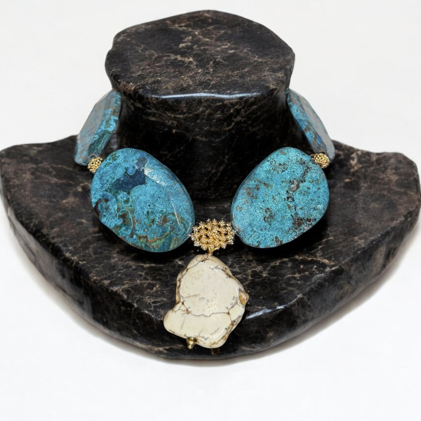 statement Necklace with turquoise and howlite gemstones on a black stone stand