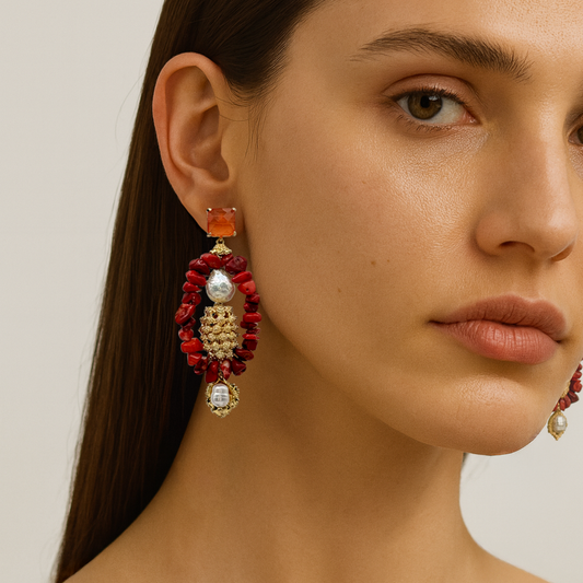 Close-up of a woman wearing red and gold earrings with a neutral background