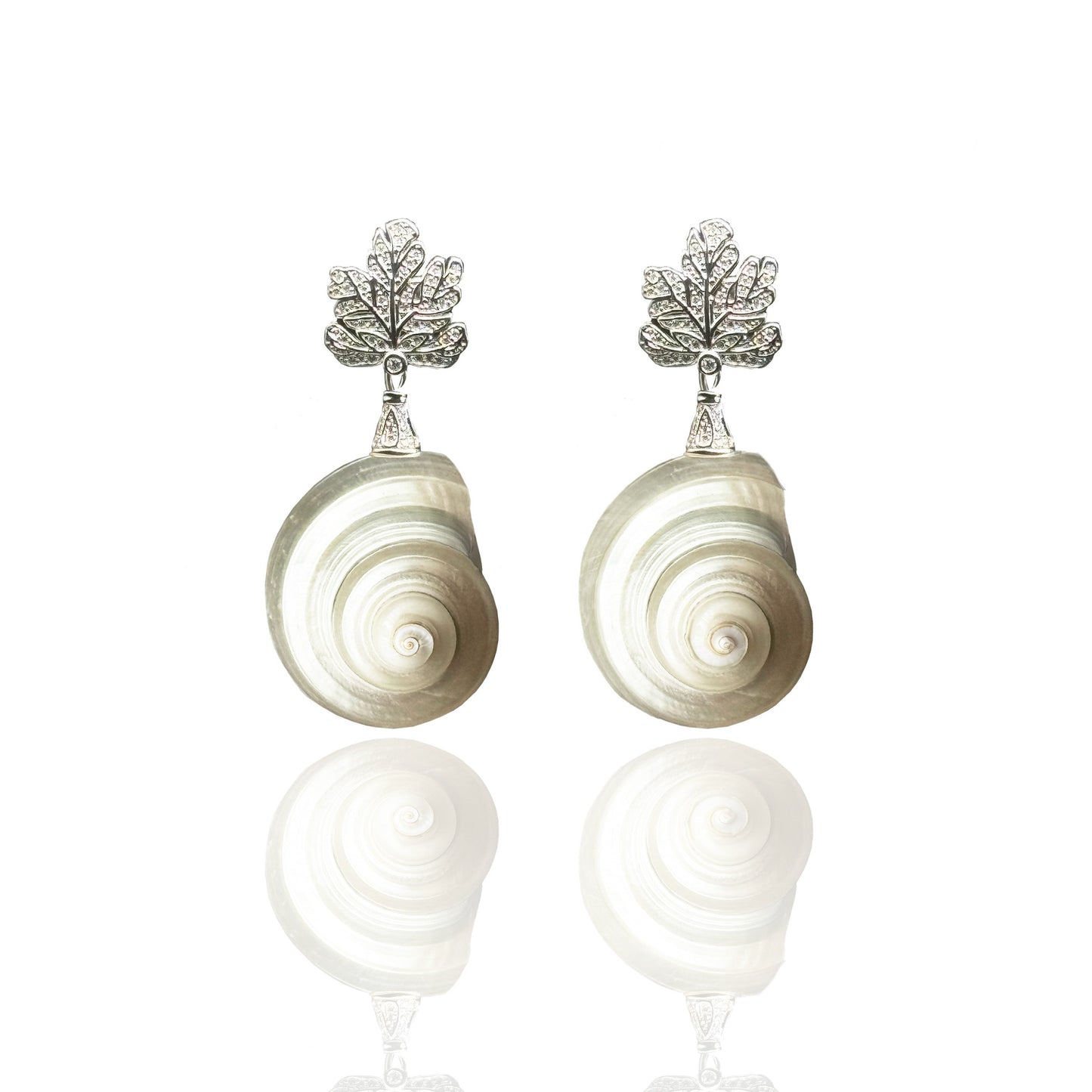 Pair of shell-shaped earrings with silver leaf-like tops on a white background