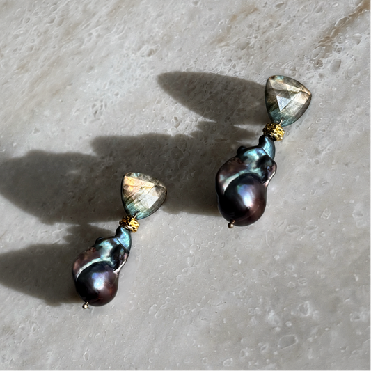 Handcrafted drop earrings pairing faceted flashing labradorite with lustrous black baroque pearls on sterling silver posts. The stone of magic meets the pearl of the moon — quietly dramatic, endlessly wearable.